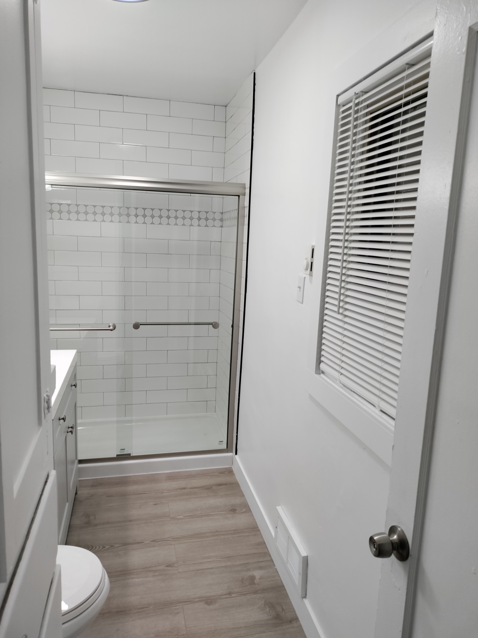 Completed Utah bathroom shower remodel with white tile and updated flooring