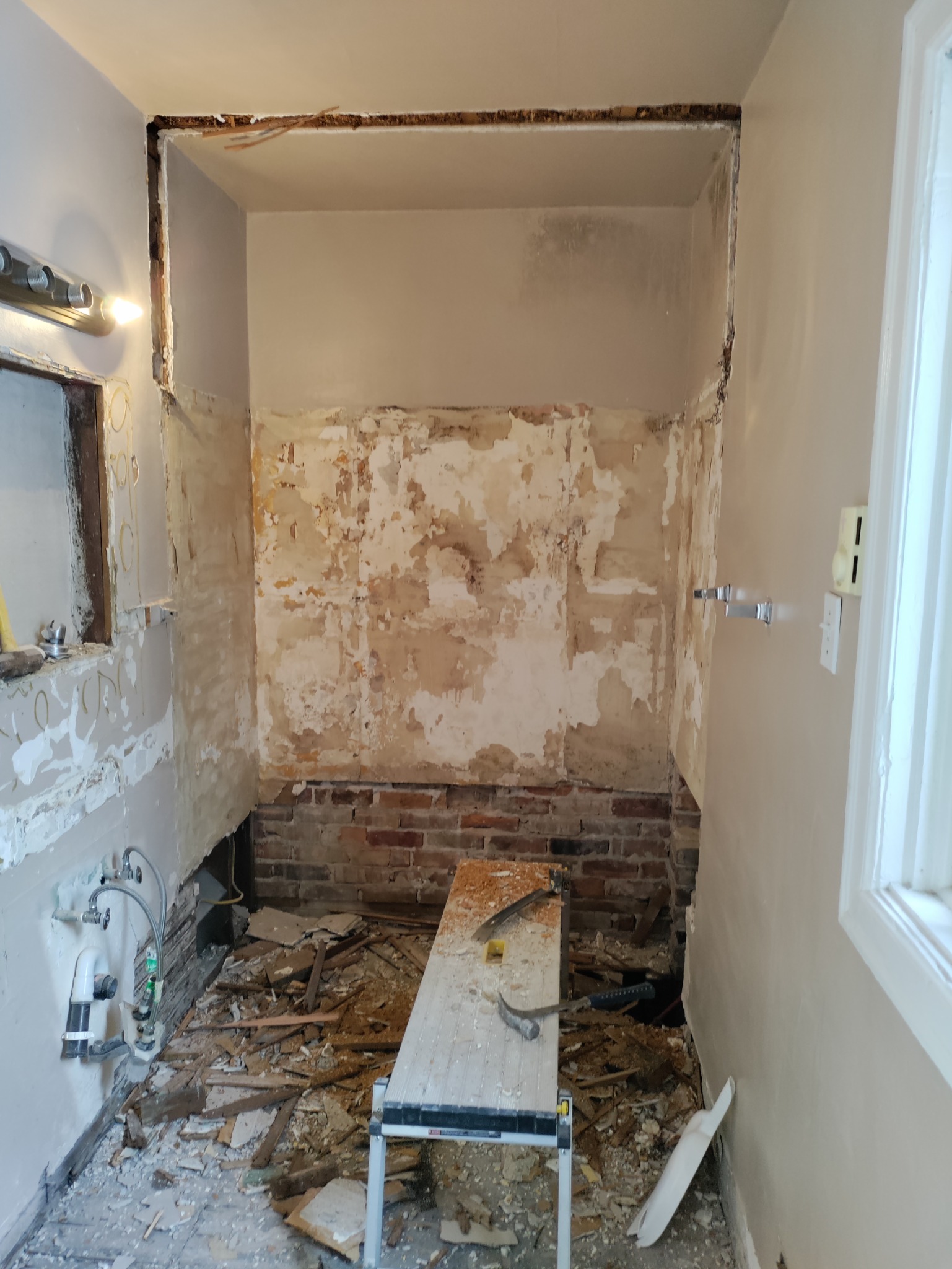 Shower demo with exposed brick and old wall substrate during Utah remodel