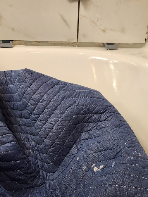 Bathroom tub protected during remodeling with visible tile and wall transition issues